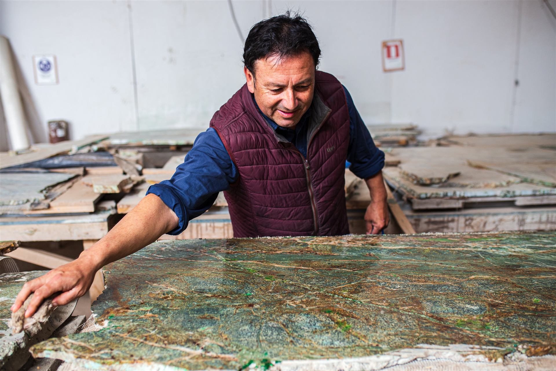 Maestro de CUSTONE revisando una plancha de roca natural de cobre en el taller